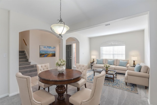 dining room featuring visible vents, arched walkways, carpet, baseboards, and stairs