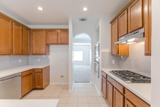 kitchen with backsplash, light tile patterned floors, and stainless steel appliances