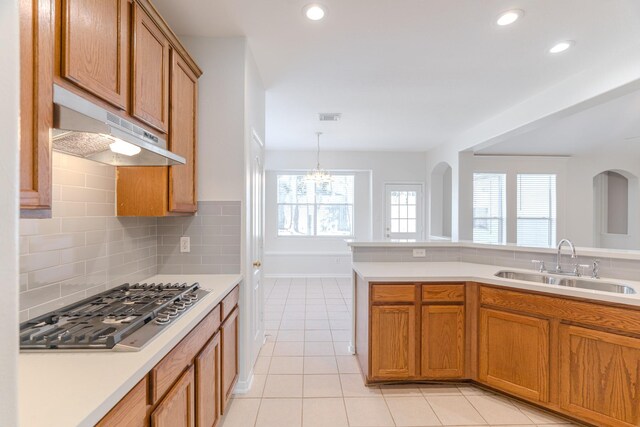 kitchen with sink, hanging light fixtures, an inviting chandelier, tasteful backsplash, and stainless steel gas stovetop