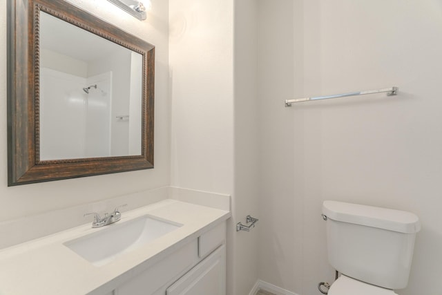 bathroom featuring toilet, vanity, and baseboards