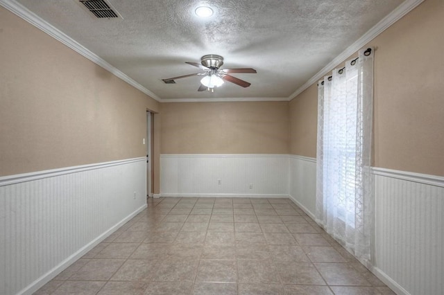 spare room with ceiling fan, light tile patterned floors, a textured ceiling, and ornamental molding