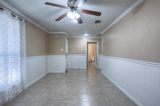 tiled spare room featuring crown molding, ceiling fan, and a textured ceiling