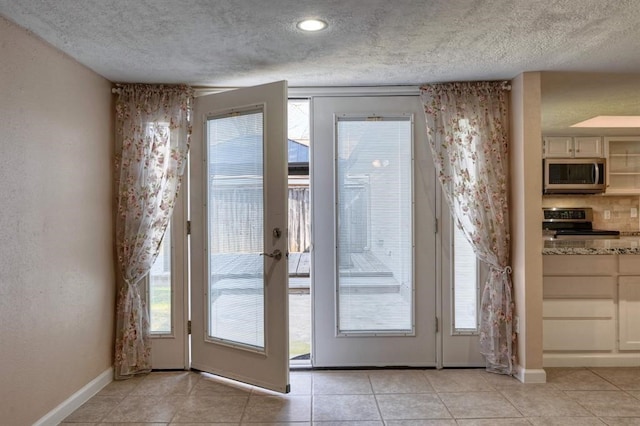 doorway to outside featuring light tile patterned floors and a textured ceiling