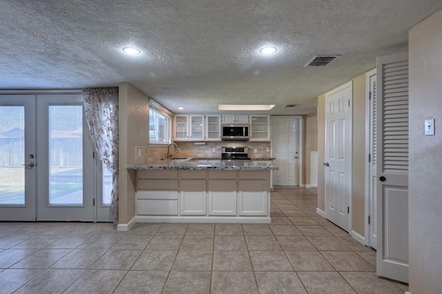 kitchen with kitchen peninsula, french doors, a textured ceiling, and stainless steel appliances