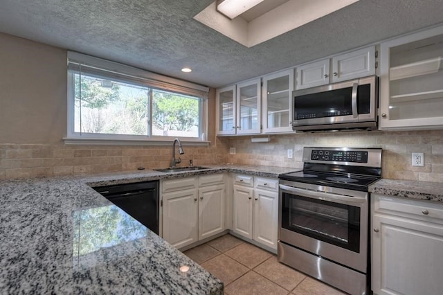 kitchen with tasteful backsplash, white cabinetry, light tile patterned floors, and appliances with stainless steel finishes