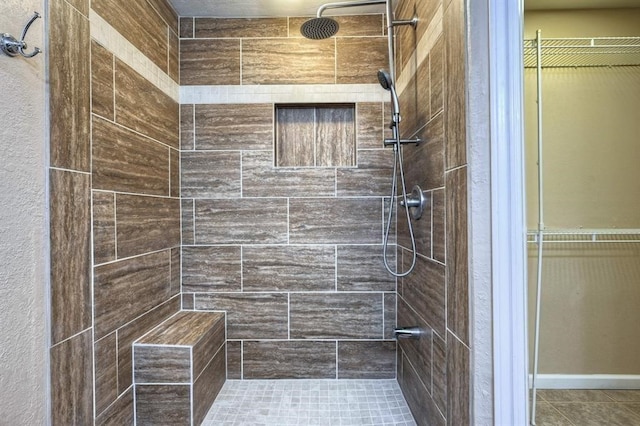 bathroom with tile patterned flooring and a tile shower