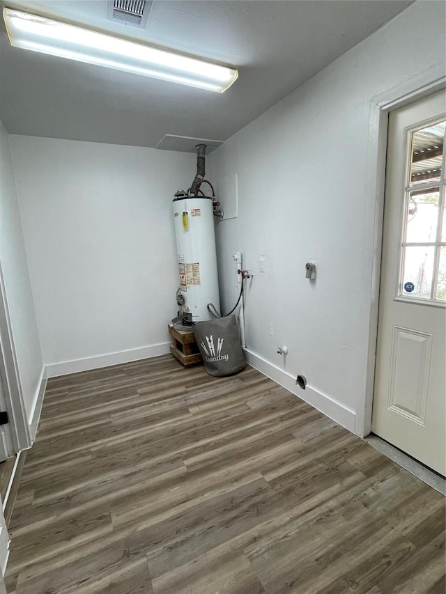 clothes washing area featuring dark hardwood / wood-style flooring and gas water heater