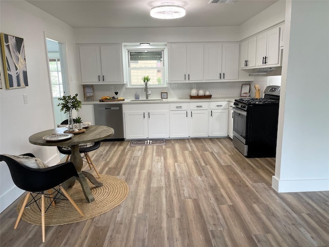 kitchen with appliances with stainless steel finishes, backsplash, white cabinetry, and sink