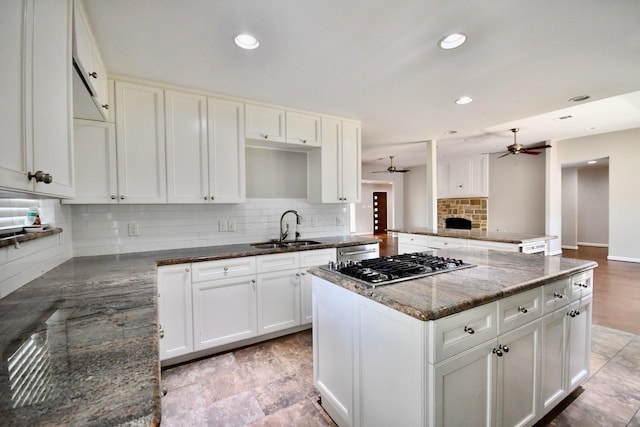 kitchen with white cabinetry, kitchen peninsula, sink, and dark stone counters