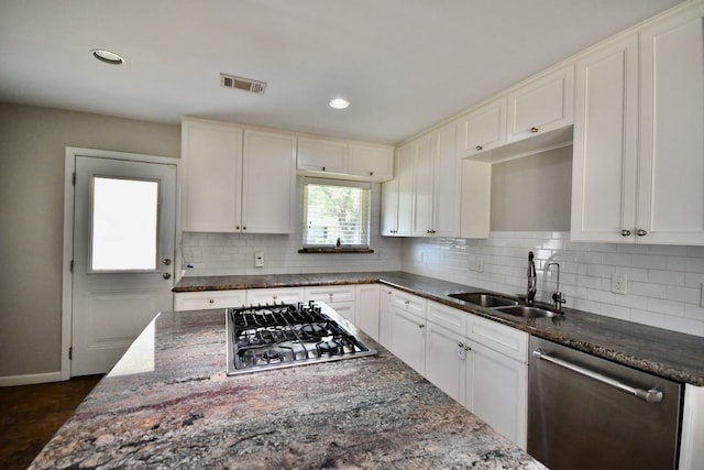 kitchen featuring sink, stainless steel appliances, tasteful backsplash, dark stone countertops, and white cabinets