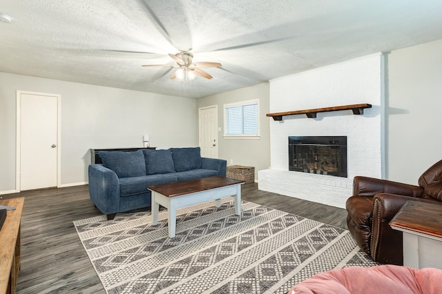 living room with ceiling fan, dark hardwood / wood-style flooring, a textured ceiling, and a brick fireplace