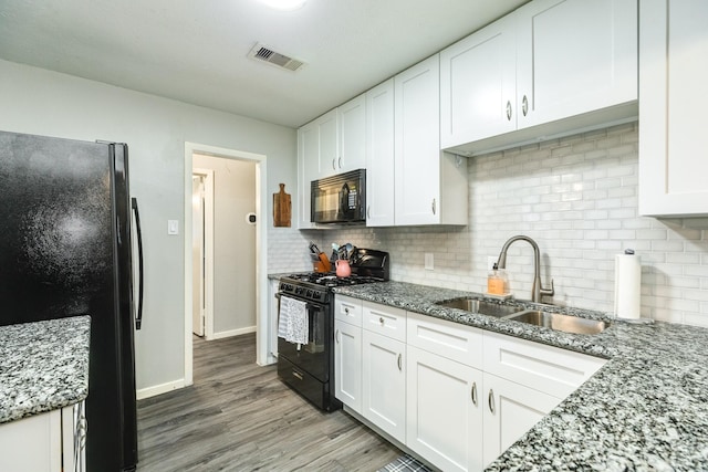 kitchen with light stone countertops, sink, white cabinets, and black appliances