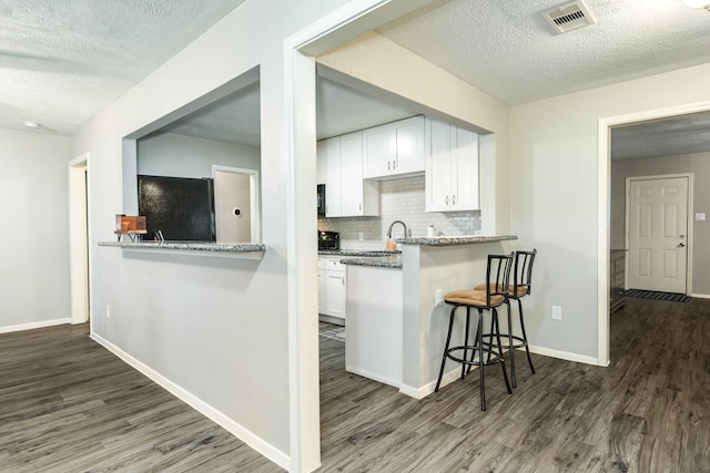 kitchen with white cabinets, light stone counters, kitchen peninsula, and tasteful backsplash