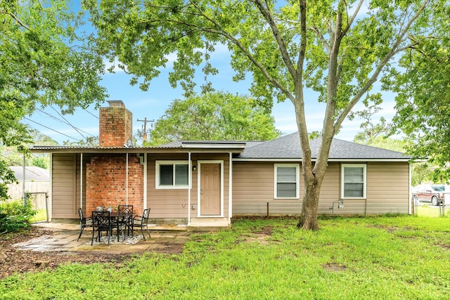 back of house with a patio and a lawn