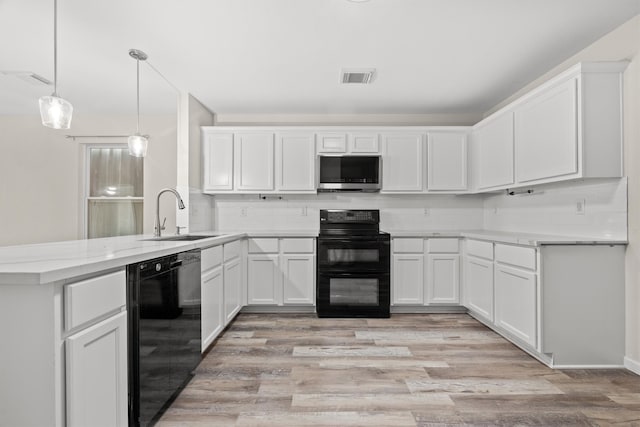 kitchen with white cabinetry, sink, kitchen peninsula, pendant lighting, and black appliances