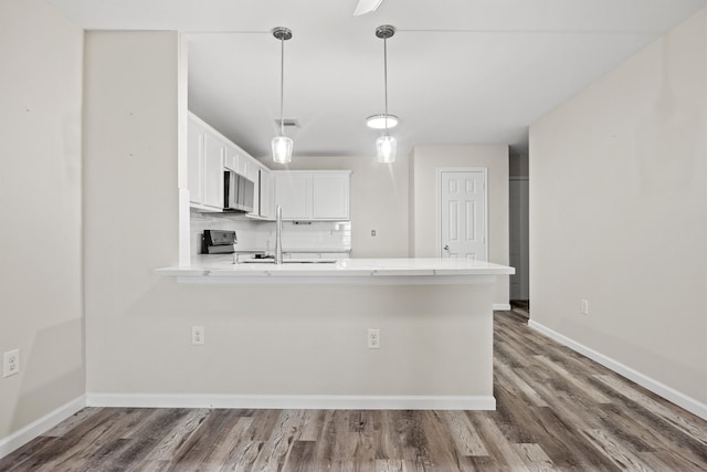 kitchen with white cabinetry, black stove, kitchen peninsula, decorative light fixtures, and hardwood / wood-style flooring