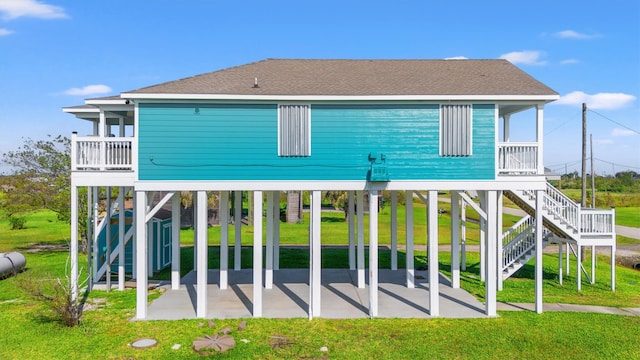 rear view of house featuring a carport, a balcony, a yard, a storage unit, and a patio