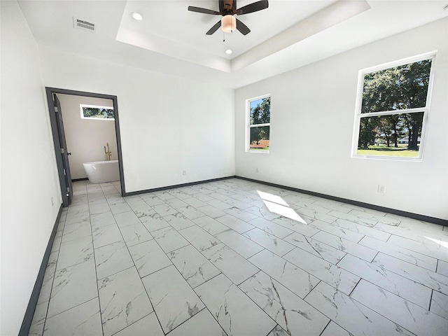 spare room with ceiling fan and a raised ceiling