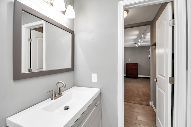 bathroom with track lighting, wood-type flooring, and vanity