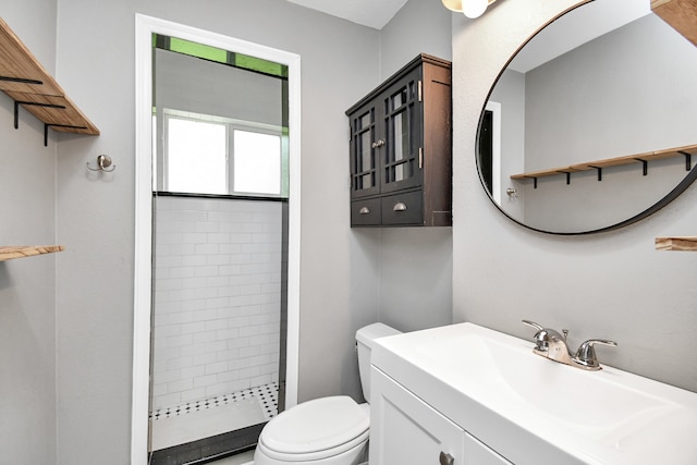 bathroom featuring toilet, vanity, and tiled shower