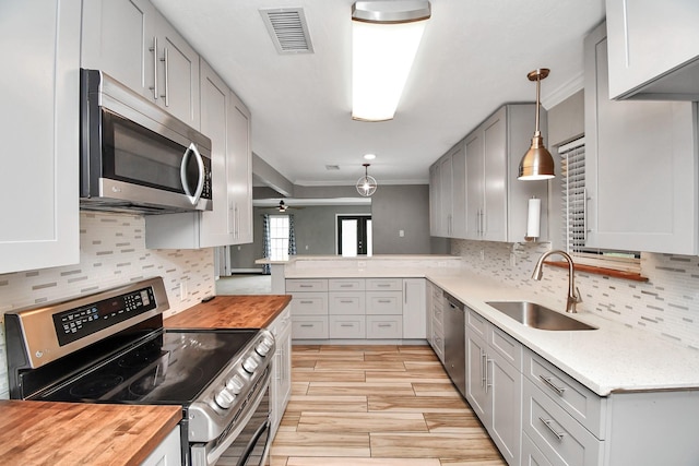 kitchen featuring butcher block counters, sink, decorative light fixtures, and stainless steel appliances