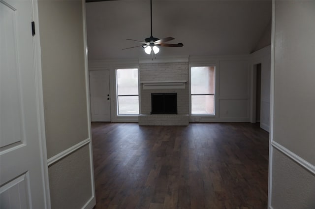 unfurnished living room with vaulted ceiling, a brick fireplace, ceiling fan, and dark wood-type flooring