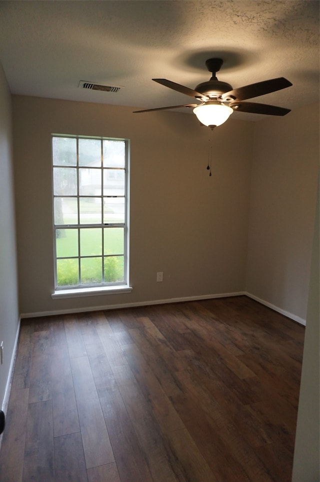 empty room with a textured ceiling, ceiling fan, and dark hardwood / wood-style floors