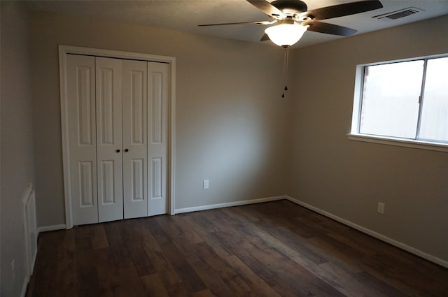 unfurnished bedroom featuring dark hardwood / wood-style flooring, ceiling fan, and a closet