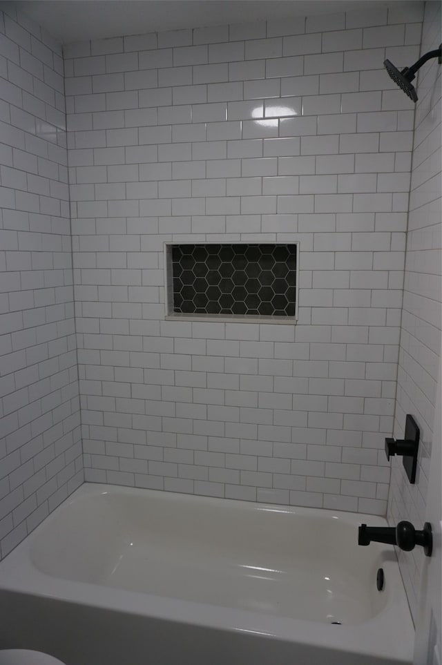 bathroom with toilet and tiled shower / bath