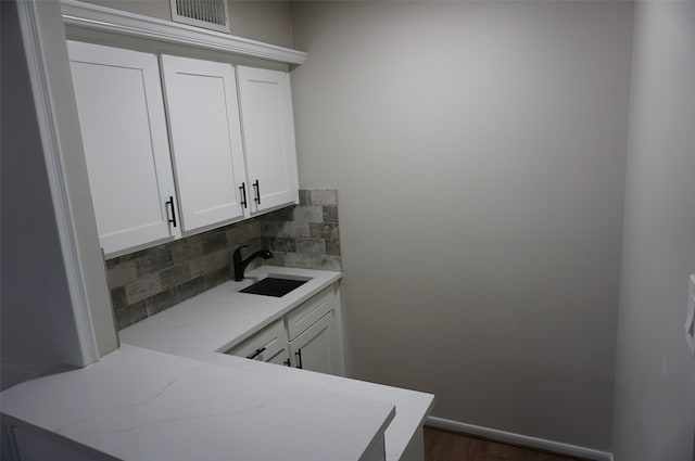 kitchen featuring decorative backsplash, light stone counters, sink, white cabinets, and dark hardwood / wood-style floors