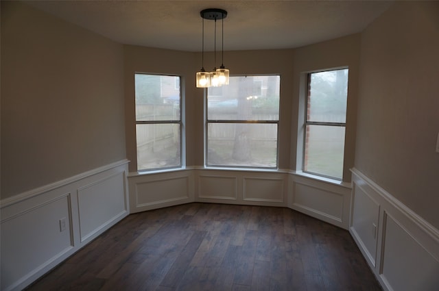 unfurnished dining area with a chandelier, dark hardwood / wood-style flooring, and plenty of natural light