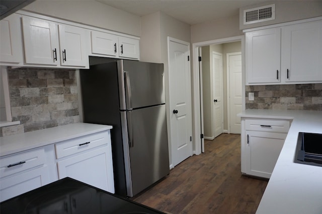 kitchen with white cabinets, decorative backsplash, dark hardwood / wood-style floors, and stainless steel refrigerator