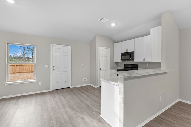 kitchen with lofted ceiling, black appliances, kitchen peninsula, light wood-type flooring, and white cabinetry