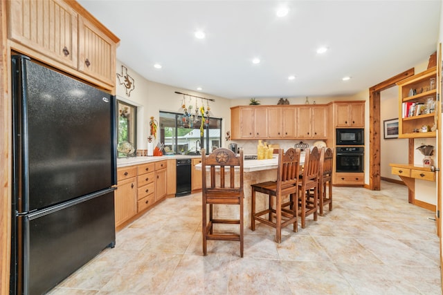 kitchen with a breakfast bar, light brown cabinetry, and black appliances