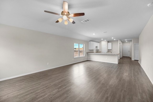 unfurnished living room with ceiling fan and dark wood-type flooring