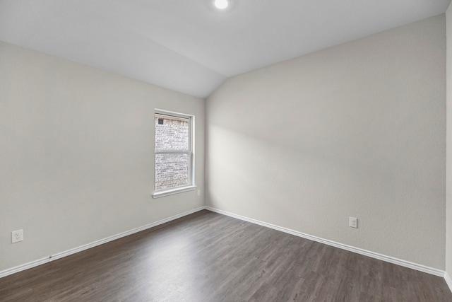 spare room with dark hardwood / wood-style flooring and vaulted ceiling