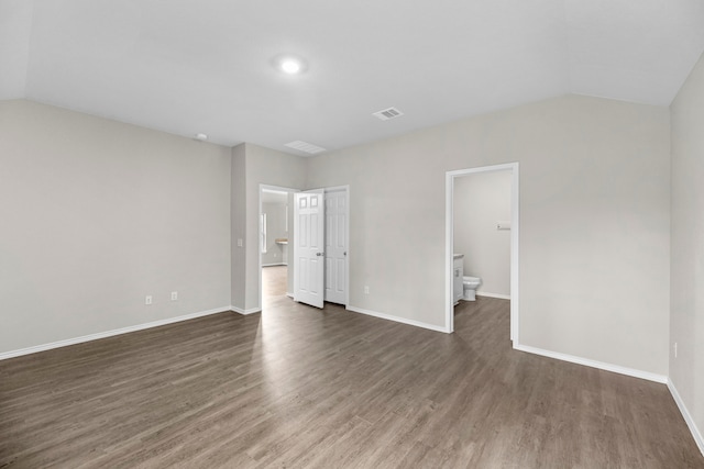 spare room featuring vaulted ceiling and dark hardwood / wood-style floors