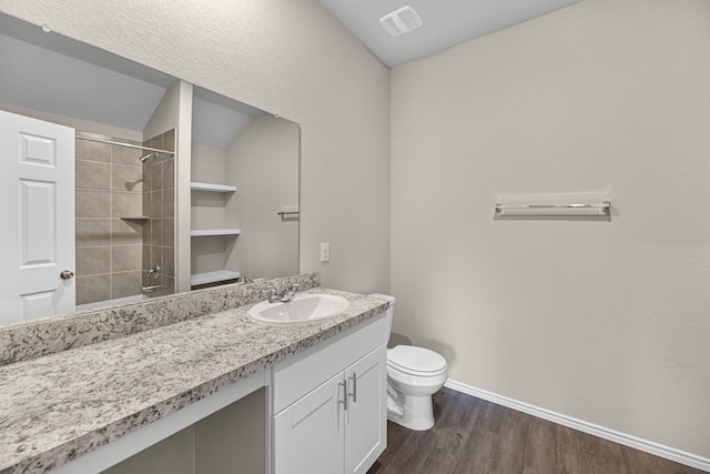 bathroom featuring tiled shower, vanity, hardwood / wood-style flooring, and toilet