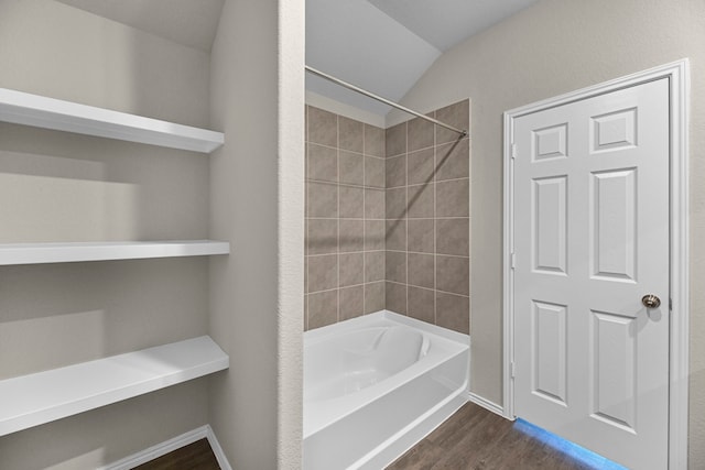 bathroom featuring hardwood / wood-style floors, tiled shower / bath combo, and vaulted ceiling