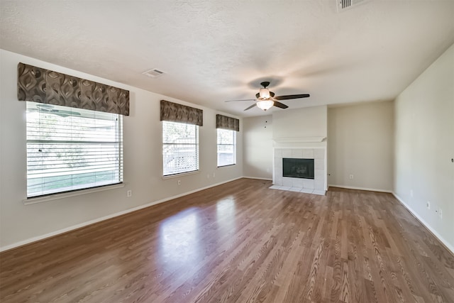 unfurnished living room with a fireplace, wood-type flooring, a textured ceiling, and ceiling fan