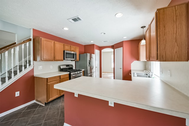 kitchen with sink, stainless steel appliances, kitchen peninsula, pendant lighting, and a textured ceiling