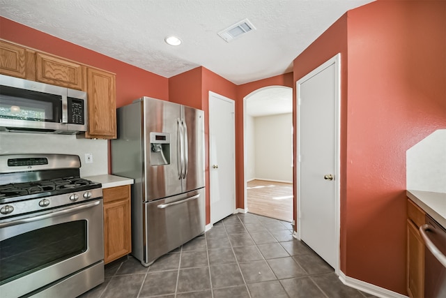 kitchen with dark tile patterned flooring, a textured ceiling, and appliances with stainless steel finishes