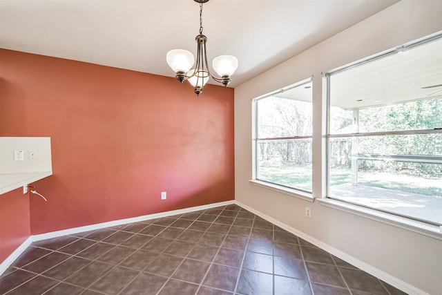 empty room with an inviting chandelier and dark tile patterned floors