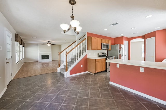 kitchen featuring pendant lighting, ceiling fan with notable chandelier, stainless steel appliances, and dark wood-type flooring