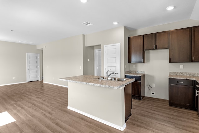 kitchen with wood-type flooring and a kitchen island with sink