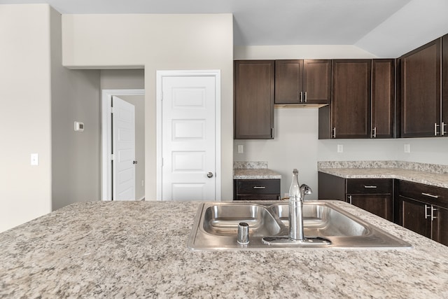 kitchen with dark brown cabinets, sink, and vaulted ceiling