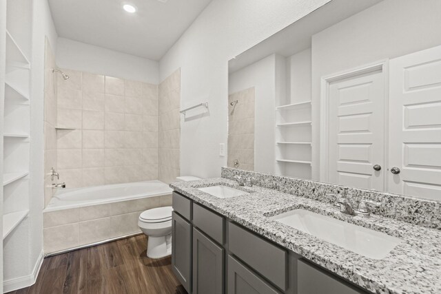 full bathroom featuring wood-type flooring, tiled shower / bath, vanity, and toilet