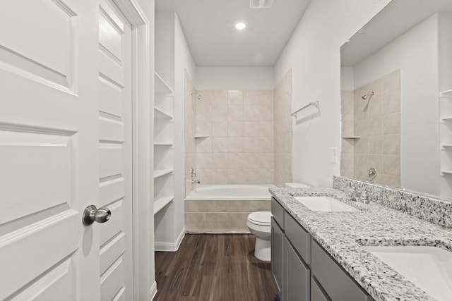 full bathroom with wood-type flooring, toilet, tiled shower / bath combo, and vanity