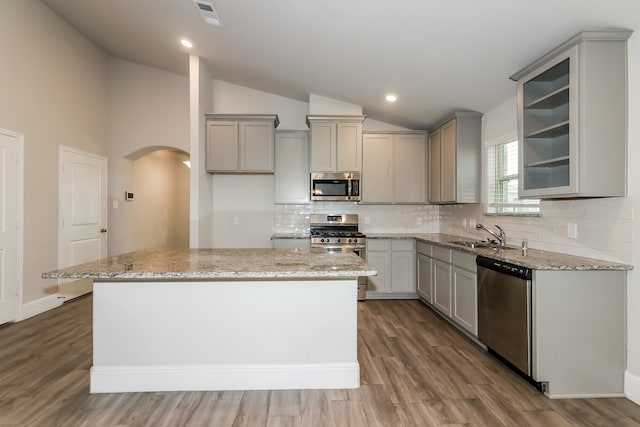 kitchen featuring hardwood / wood-style flooring, a kitchen island, lofted ceiling, and appliances with stainless steel finishes