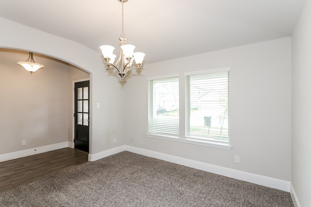 spare room with dark hardwood / wood-style flooring and an inviting chandelier